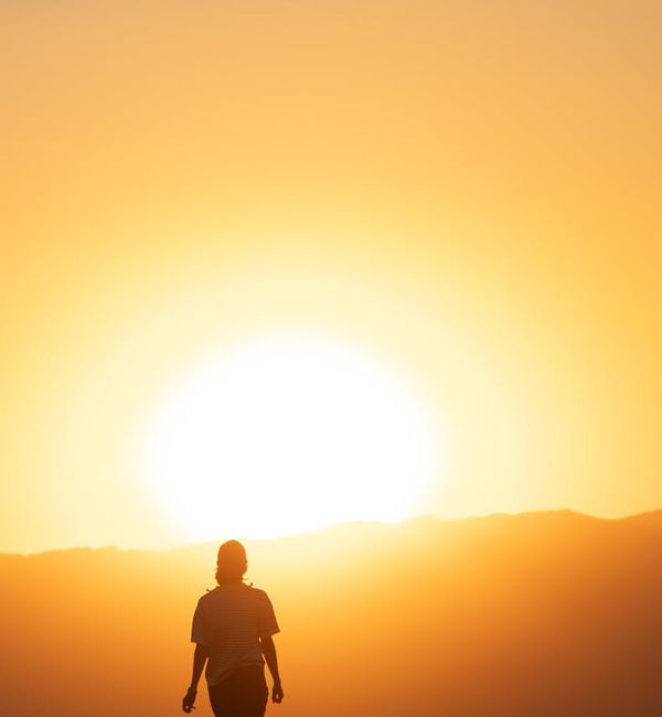 Silhouette of a person meditating at sunset with a warm glow.